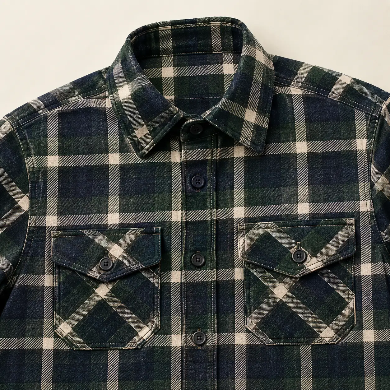 Premium plaid flannel shirt showcasing chest pockets, buttoned flaps, topstitching, reinforced seams, and garment construction details.